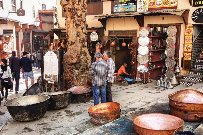 Traditional Moroccan metal artisans crafting copperware in a busy medina souk, showcasing ancestral craftsmanship