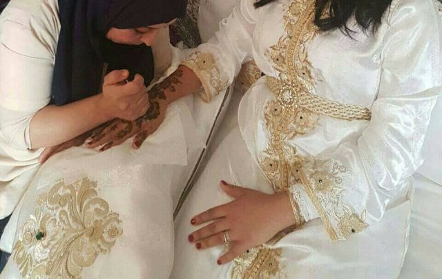 Artisane marocaine appliquant la henné sur la main d'une mariée lors de la nuit du henné