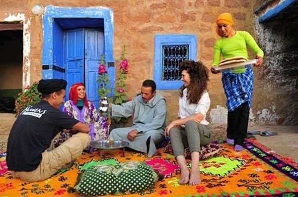 Famille marocaine accueillant des invités autour du thé dans une maison traditionnelle