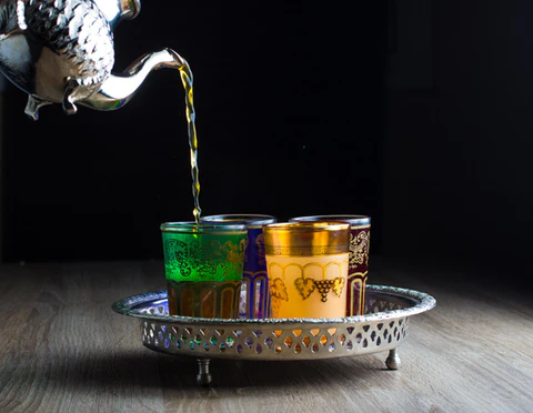 Thé marocain versé de haut dans un verre traditionnel avec mousse dorée